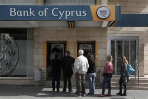 People queue up to make a transaction at an ATM outside a branch of Bank of Cyprus in Nicosia