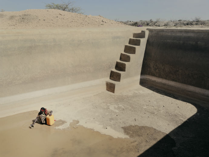 Una donna somala prende acqua da ciò che resta di una riserva idrica