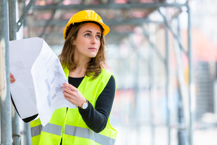 Young and cute female engineer with office blueprints. Outdoors