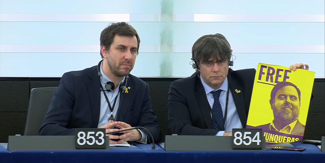 Antoni Comin (sinistra) e Carles Puidgemont alla loro prima seduta da europarlamentari. I due catalani mostrano un poster che chiede il rilascio da parte delle autorità spagnole di Oriol Junqueras, eletto europarlamentare ma in carcere in Spagna [Strasburgo, 13 gennaio 2020]