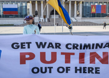 A woman holding a Ukranian national flags and a banner takes part in a protest ahead of a visit by Russian President Vladimir Putin in Ulaanbaatar, Mongolia's capital city on September 2, 2024. (Photo by Byambasuren BYAMBA-OCHIR / AFP)