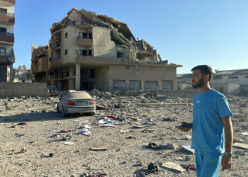 A man walks past destruction caused by Israeli airstrikes in the Masaken neighbourhood on the outskirts of Tyre on September 26, 2024 (Photo by Hassan FNEICH / AFP)