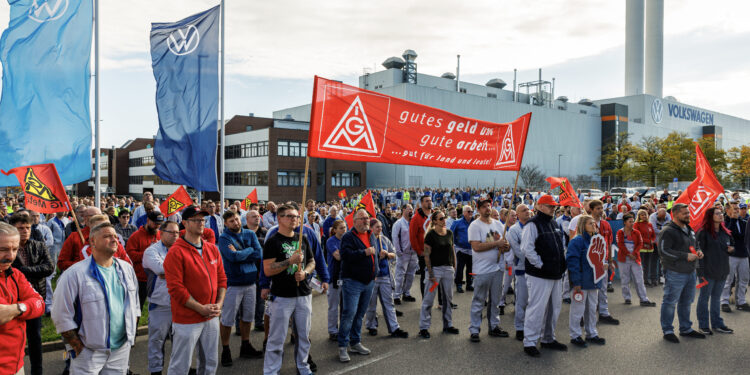 Employees of the Volkswagen plant in Zwickau stand on the factory premises during an information event organised by the Works Council of Volkswagen Saxony in Zwickau, eastern Germany, on October 28, 2024. Ailing auto giant Volkswagen plans to close at least three factories in Germany and slash tens of thousands of jobs as part of drastic cost-savings drive, workers' representatives said October 28, 2024, calling the proposed cuts "of historic dimensions". The plan laid out by management, which affects the namesake VW brand, also includes a 10-percent pay cut for all staff, the company's powerful works council said in an update to staff. (Photo by JENS SCHLUETER / AFP)