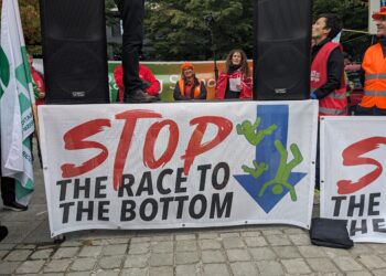 Uno striscione alla manifestazione in piazza Jean Rey che recita "Stop alla corsa al ribasso" (foto: Fabiana Luca)