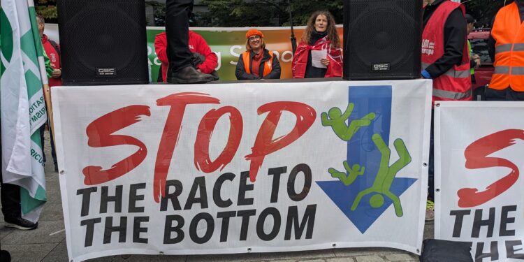 Uno striscione alla manifestazione in piazza Jean Rey che recita "Stop alla corsa al ribasso" (foto: Fabiana Luca)